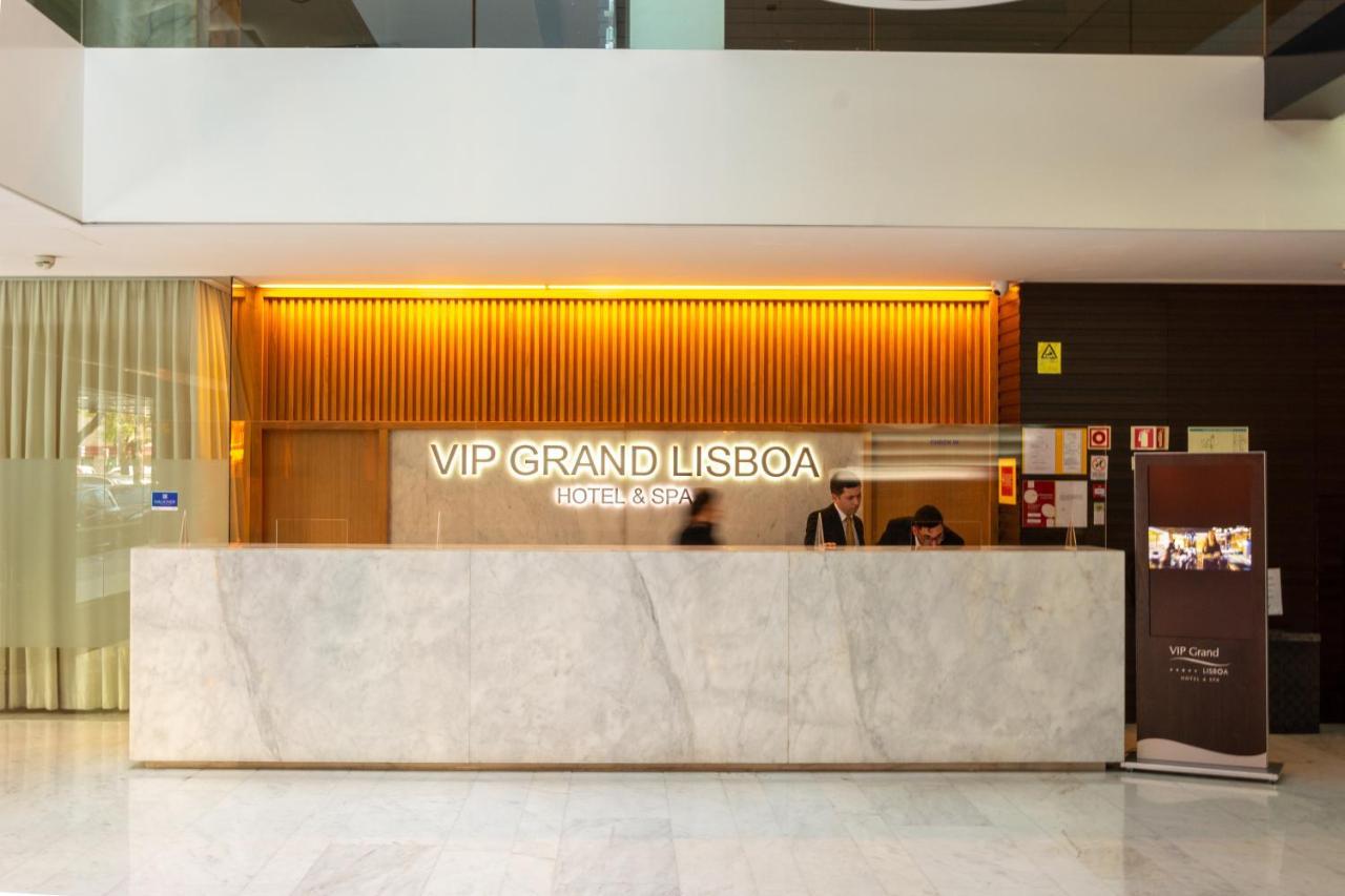 Vip Grand Lisboa Hotel & Spa Exterior photo The image depicts the reception area of the VIP Grand Lisboa hotel. The reception desk is made of marble, and the hotel's name is prominently displayed in illuminated lettering. The background features wooden paneling with warm lighting, creating an 