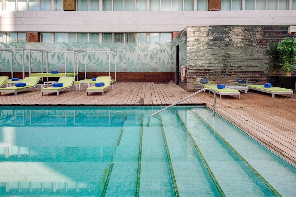 Vip Grand Lisboa Hotel & Spa Exterior photo The image shows a swimming pool area surrounded by modern lounge chairs. The pool has clear water, and the design features a few steps leading into it. There are light green lounge chairs set up with blue cushions on a wooden deck surrounding the poo