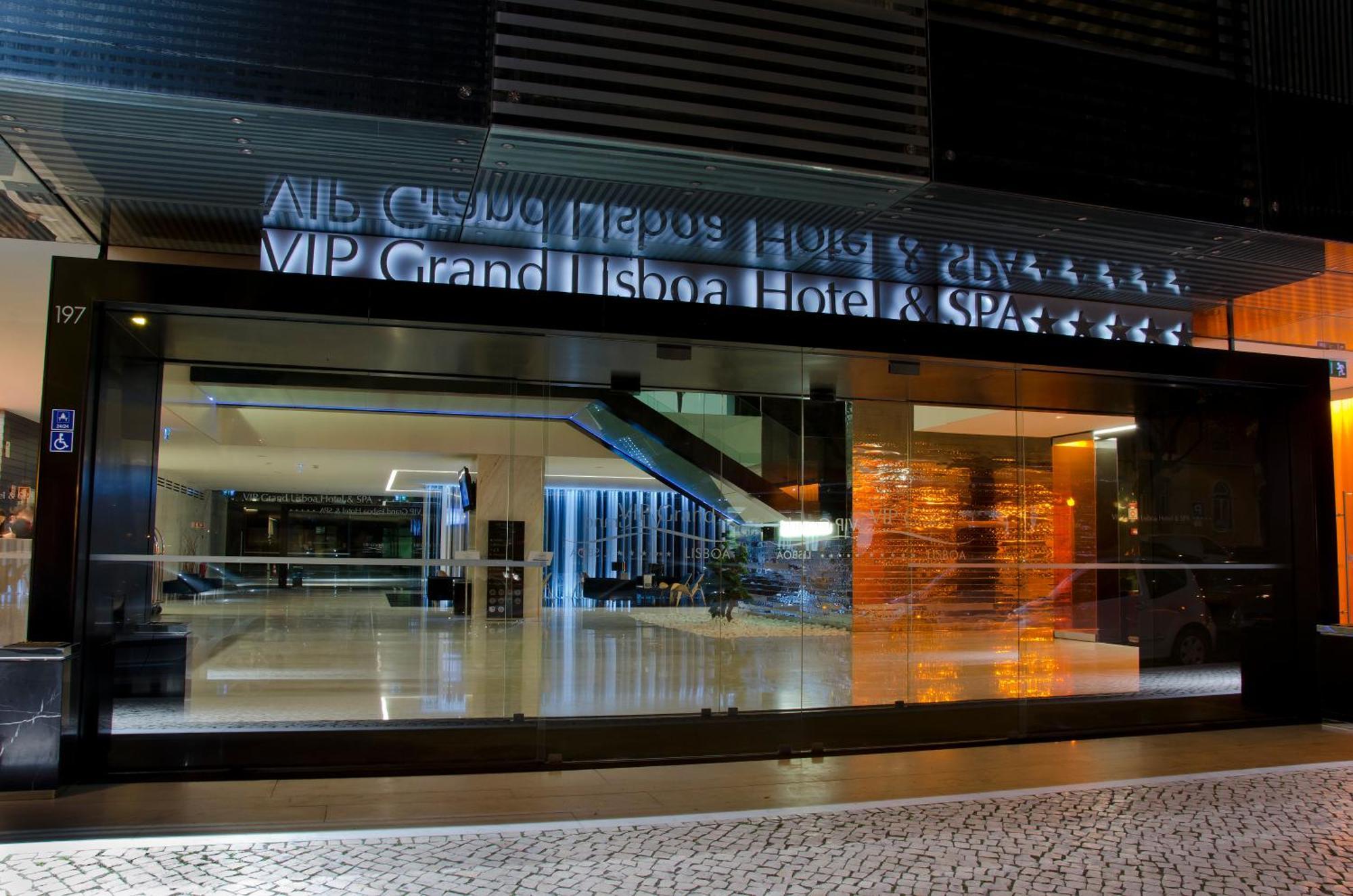 Vip Grand Lisboa Hotel & Spa Exterior photo The photo shows the entrance of a hotel, featuring a modern glass façade illuminated at night. The visible text indicates the name of the hotel as "MP Grand Lisboa Hotel & SPA," accompanied by a star rating. The interior appears spacious and elegantl