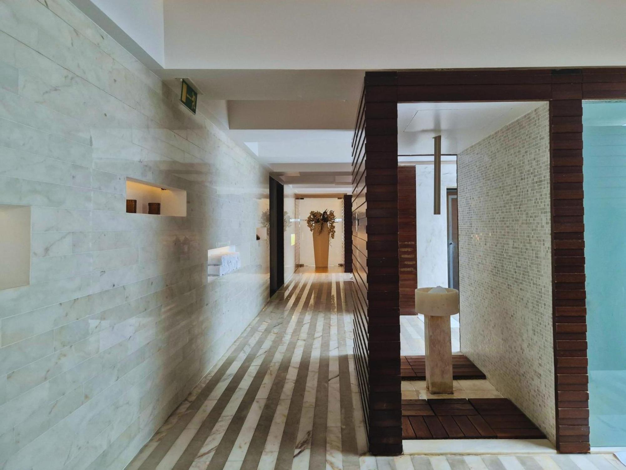 Vip Grand Lisboa Hotel & Spa Exterior photo The photo depicts a modern interior space, likely in a hotel or spa. It features a long, narrow hallway with minimalist design elements. The walls are a light-colored stone, and there are wooden features creating contrasts. 

The floor is designed wi