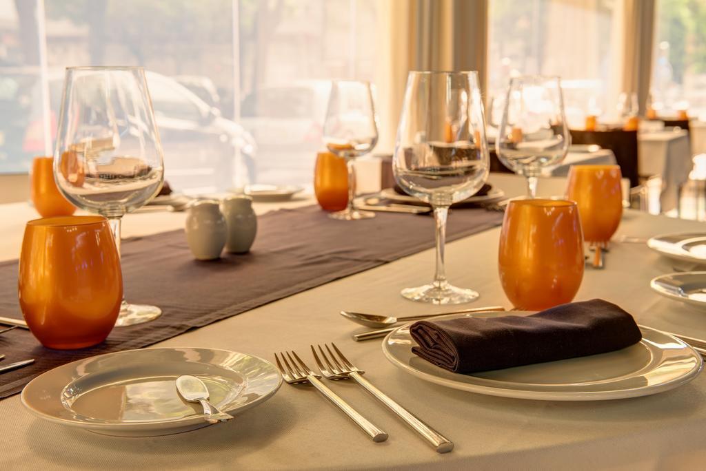 Vip Grand Lisboa Hotel & Spa Exterior photo The photo shows a beautifully set dining table. There are several glassware items, including wine glasses and water glasses, placed neatly on the table. The table is adorned with orange candle holders, adding a warm touch to the setting. The tableclo